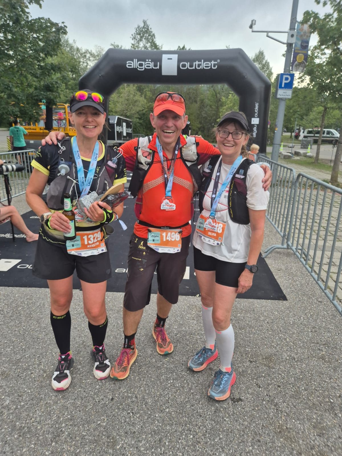 Harald Pfeiffer, Silvia Müller und Kerstin Langreder mit Medaillen im Zielbogen des Allgäu Panorama Marathons